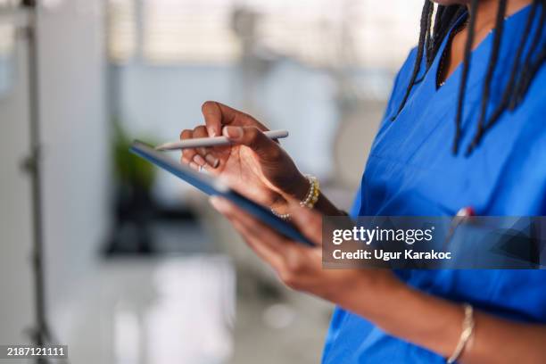 acérquese a un trabajador de la salud con manos de bata azul usando una tableta digital. - informe-médico-electrónico fotografías e imágenes de stock