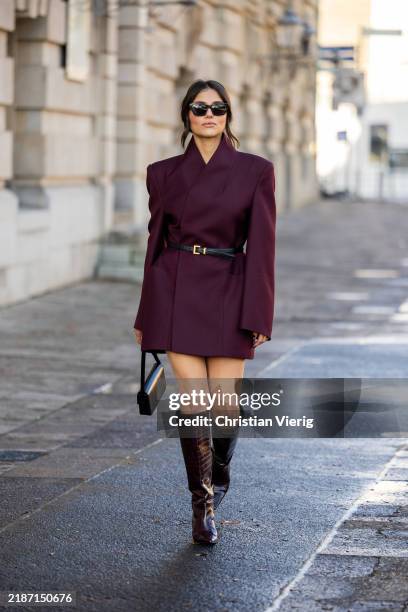 Aylin Sengül wears burgundy blazer Sourceunknown, knee high boots Zara, sunglasses & belt YSL, bag Celine on November 27, 2024 in Berlin, Germany.