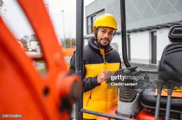 construction professional with digital tablet by excavator - grondverzetmachine stockfoto's en -beelden