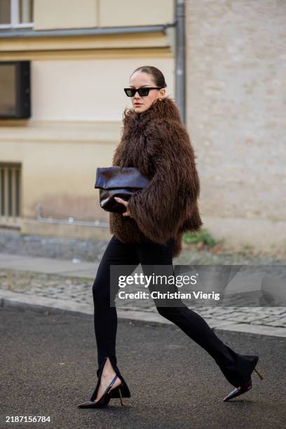 Berna Bilbey wears brown shearling faux fur jacket Ducie London, black pants Edited, heels Saint Laurent, burgundy bag &Other Stories, sunglasses...