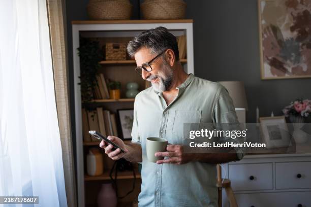man drinking coffee and using phone - oudere mannen stockfoto's en -beelden