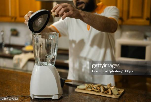 man pouring ginger into the blender in the kitchen - liquidiser stock pictures, royalty-free photos & images