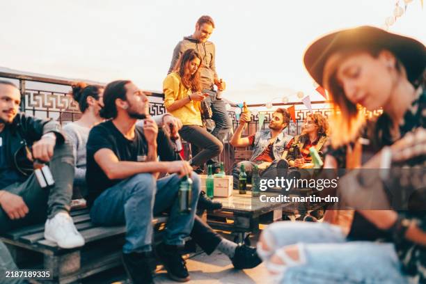 friends drinking and partying on the rooftop - individual event stock pictures, royalty-free photos & images