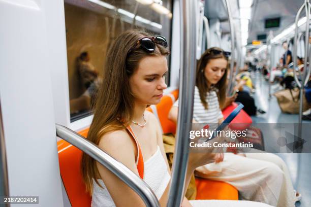 two female friends using phones on the subway train - location tracking stock pictures, royalty-free photos & images