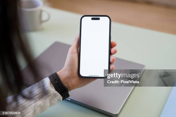 woman holding smartphone with blank screen at office desk - iphone stock pictures, royalty-free photos & images