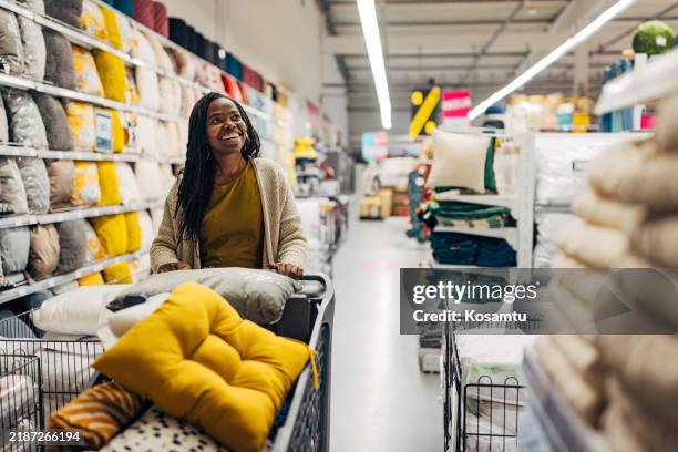 femme noire souriante appréciant de choisir des oreillers de qualité à acheter dans un grand magasin - équipement domestique photos et images de collection