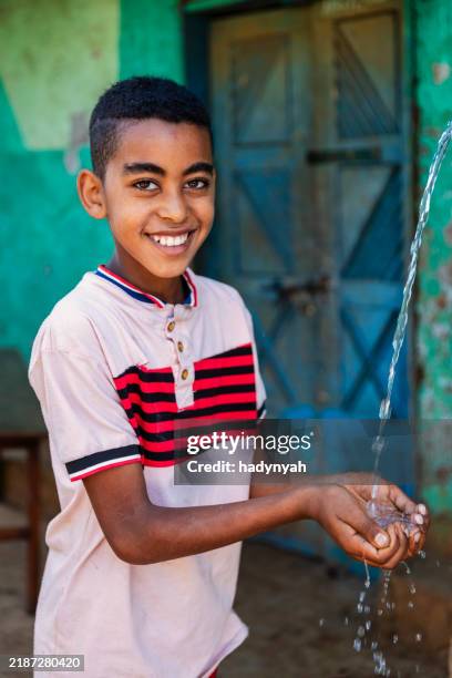 african young boy drinking fresh water, east africa - ethiopian ethnicity stock pictures, royalty-free photos & images