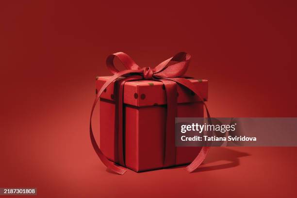 red gift box with bow ribbon on red gradient background - birthday card table stock pictures, royalty-free photos & images