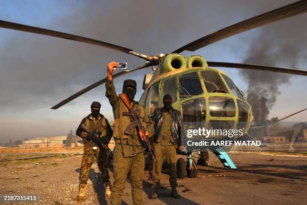 Anti-regime fighters pose for a picture with an army helicopter on the tarmac at the Nayrab military airport in the northern Syrian city of Aleppo on...