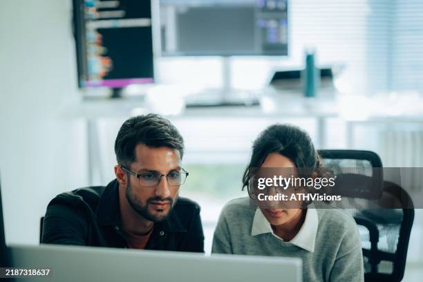 two hispanic programmers collaborating on software development in a modern tech workspace - application programming interface stockfoto's en -beelden