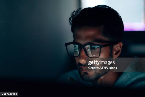 specialista it ispanico che si concentra sui dati e sulla programmazione in uno spazio di lavoro buio e tecnologico - programmazione televisiva foto e immagini stock