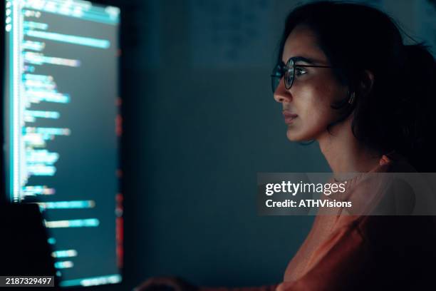 focused hispanic latin female programmer working on code at night in a high-tech workspace - datawetenschapper stockfoto's en -beelden