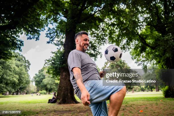 mature man playing soccer on the public park - kick ups stock pictures, royalty-free photos & images