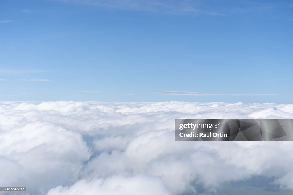 Aerial view of cotton clouds and blue skies shot from commercial airplane