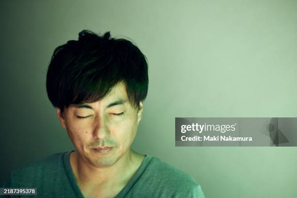 portrait of a man with his eyes closed, taken in a studio - low key lighting stock pictures, royalty-free photos & images