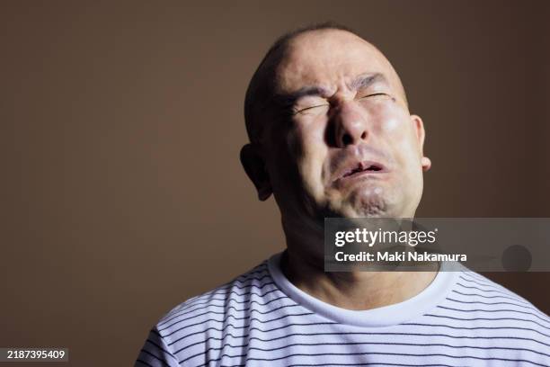 mature man in studio against brown background with high - grimace de crispation photos et images de collection