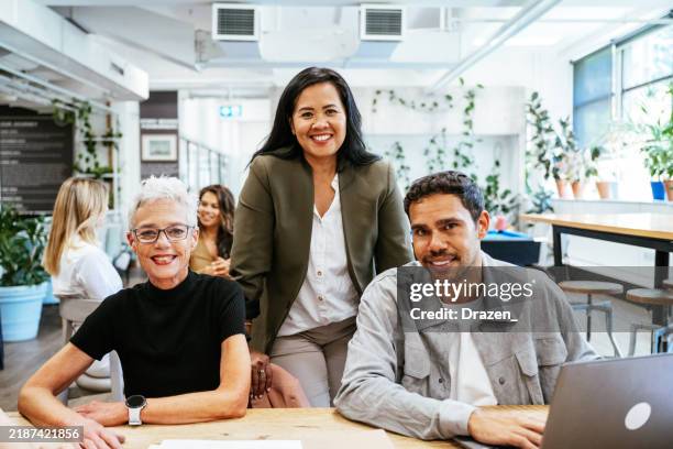 grupo de tres empresarios diversos que trabajan en una moderna oficina de coworking y miran a la cámara - cultura australiana fotografías e imágenes de stock