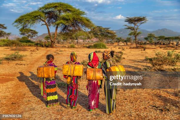 young african women carrying water from the well, ethiopia, africa - etiopia foto e immagini stock