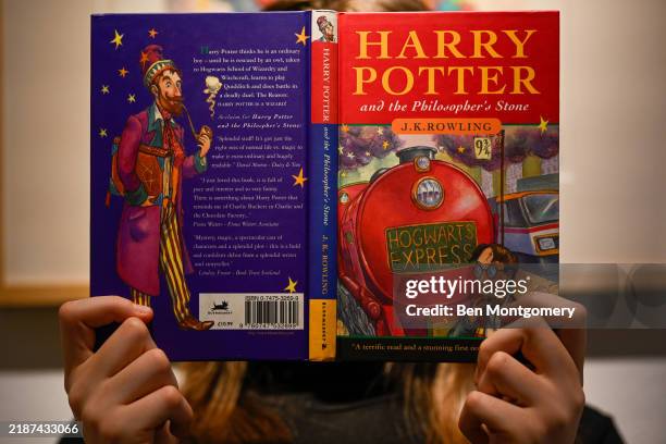 An arts handler of Christie's holds an original copy of Harry Potter and the Philosopher's Stone book by J.K. Rowling on November 29, 2024 in London,...