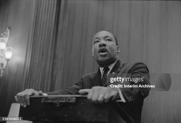 African American civil rights leader Martin Luther King, Jr holds onto the lectern as he speaks at a press conference regarding the Senate debate...