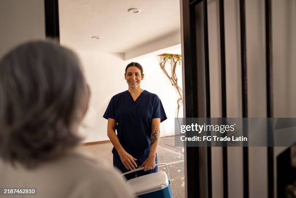 mujer enfermera adulta media que llega a la casa del paciente - visita a domicilio fotografías e imágenes de stock