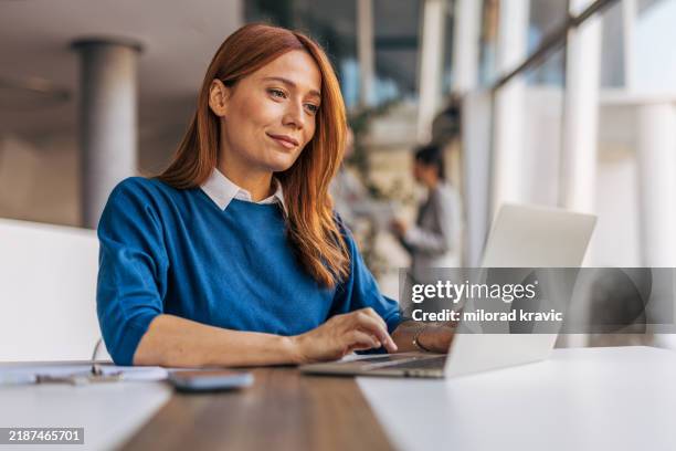 una mujer de negocios exitosa usa una computadora portátil y trabaja en la oficina - usar el ordenador fotografías e imágenes de stock