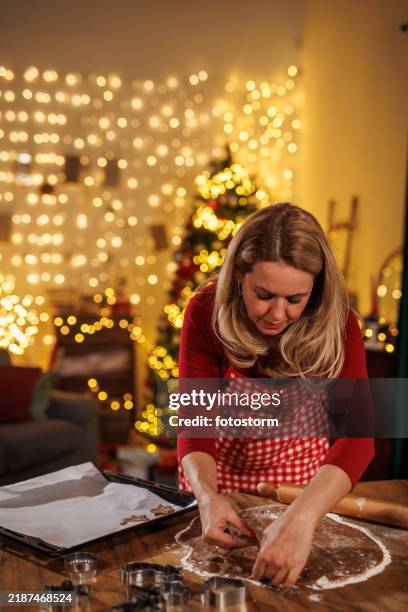 woman baking christmas cookies in a festive holiday kitchen setting - papel de cera imagens e fotografias de stock