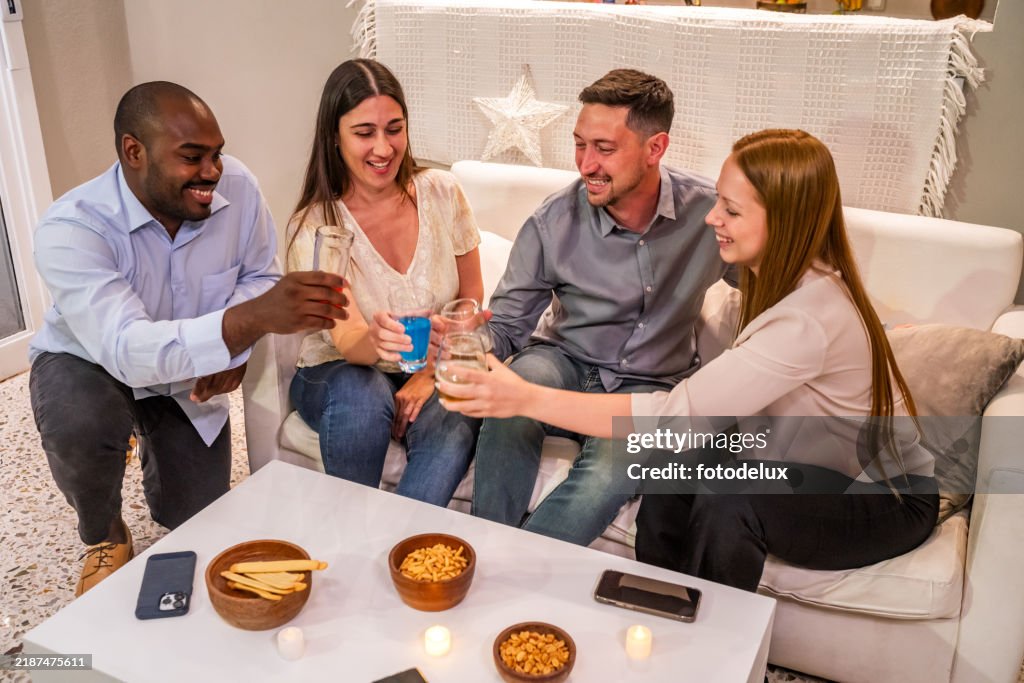 Happy Friends Toasting Drinks Together at Home Gathering