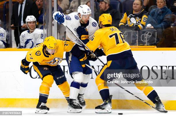 Brandon Hagel of the Tampa Bay Lightning and Brady Skjei and Luke Evangelista of the Nashville Predators battle for the puck during the second period...