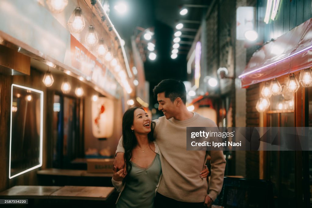 Couple having fun in narrow alleyway at night in Tokyo