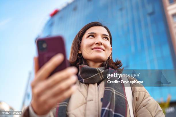 donna che usa il telefono cellulare nella strada della città. - online banking foto e immagini stock