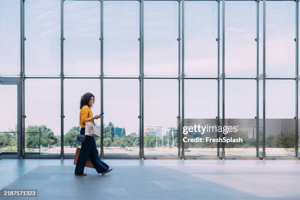 woman walking in modern building with shopping bags and smartphone - window frame stock pictures, royalty-free photos & images