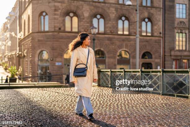 turista feliz de la mujer que camina en el puente en la ciudad - abrigo largo fotografías e imágenes de stock