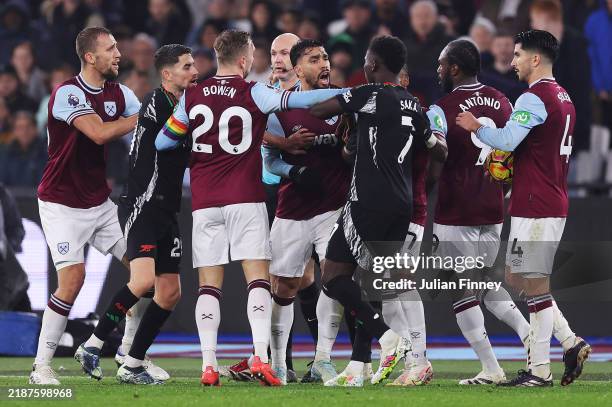 Emerson Palmieri of West Ham United clashes with Bukayo Saka of Arsenal during the Premier League match between West Ham United FC and Arsenal FC at...