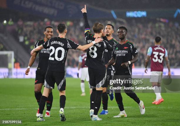 Martin Odegaard of Arsenal celebrates scoring his team's third goal from a penalty kick with teammates during the Premier League match between West...