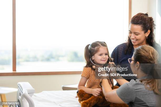 little girl wears doctor's stethoscope - pediatric nurse stock pictures, royalty-free photos & images