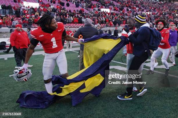 Davison Igbinosun of the Ohio State Buckeyes grabs a Michigan flag following his team's defeat against the Michigan Wolverines at Ohio Stadium on...