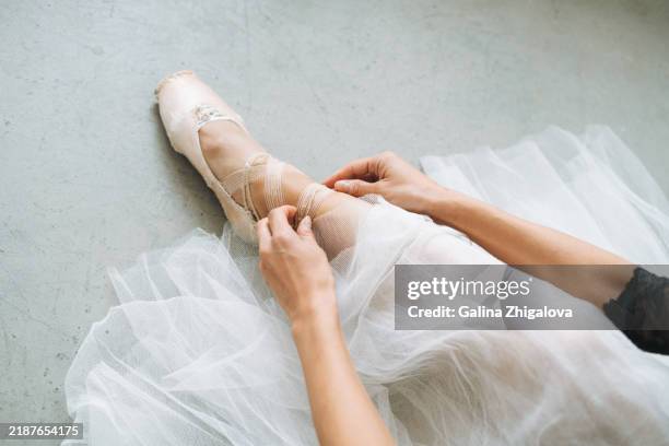 young beautiful ballerina in tutu skirt puts on pointe shoes in ballet studio - scarpette-per-danza-classica foto e immagini stock