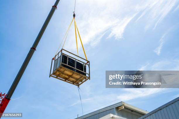 crane lifting heavy equipment against a bright blue sky - hochziehen stock-fotos und bilder