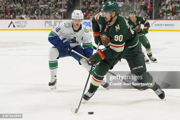 Minnesota Wild forward Marcus Johansson skates with the puck as Vancouver Canucks forward Elias Pettersson defends during an NHL game between the...