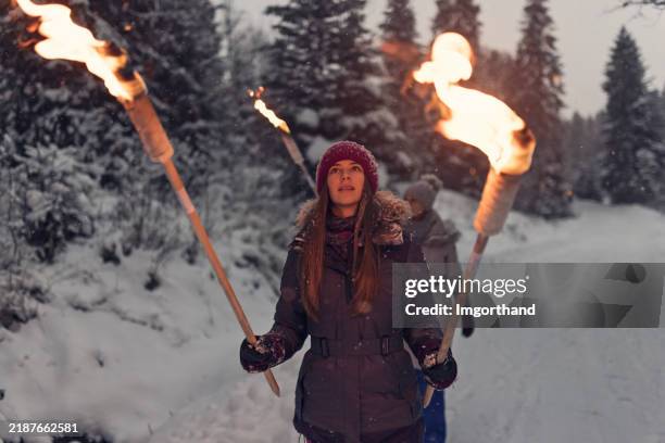 teenager-mädchen hält brennende fackeln auf einem verschneiten waldweg - fackel stock-fotos und bilder