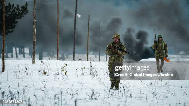 Ukrainian servicemen with firearms overcome an obstacle course during a basic combined military training on November 24, 2024 in Chernihiv Oblast,...