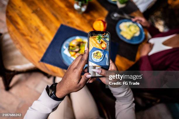 woman photographing her dish on the mobile phone at a restaurant - spanish food stock pictures, royalty-free photos & images