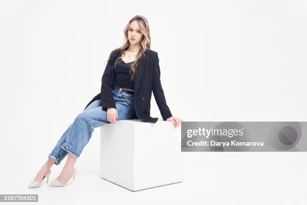 model on the shooting. a young woman is sitting on the cube on a cyclorama. - cyclo photos et images de collection