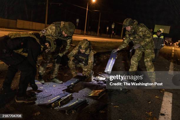 Police and emergency workers look at the pieces of a kamikaze drone with the marking Geran-2 that hit the road and damaged a five-story apartment...