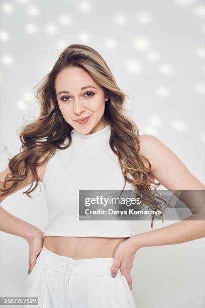 a young woman in white top and pants on white background with lights. - sleeveless stock pictures, royalty-free photos & images