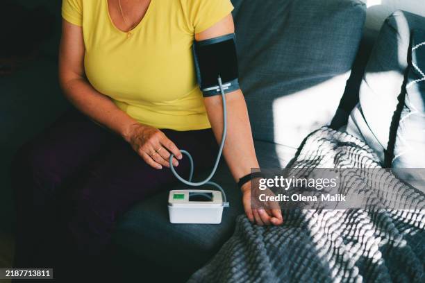 woman checking blood pressure - bluthochdruck stock-fotos und bilder