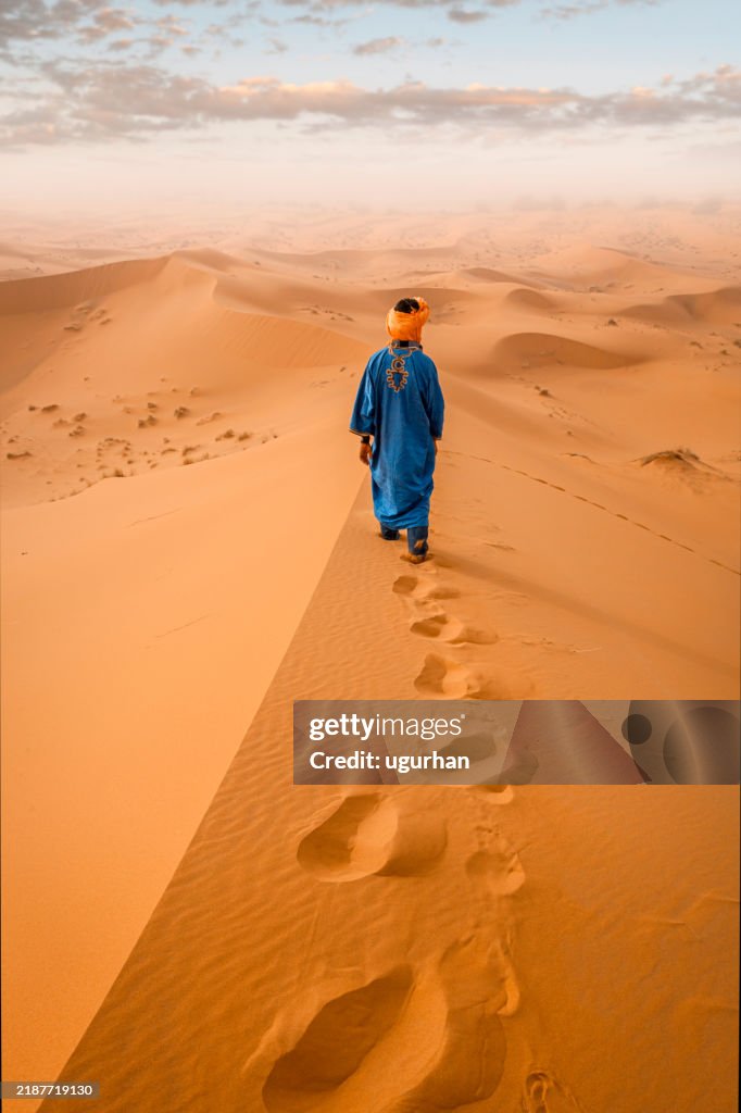 Berber man wearing traditional clothing walking in the sahara desert