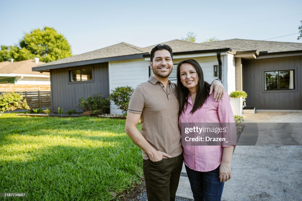 Reifes Ehepaar, das stolz vor neu gekauftem Haus posiert