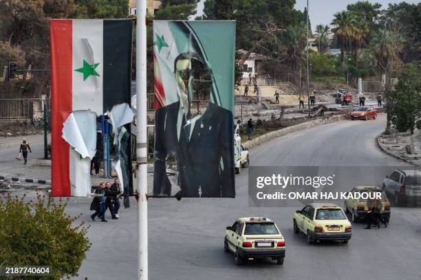 An aerial picture shows members of Syria's White Helmets civil defence service clearing vehicle carcasses and rubble from a street in Aleppo on...